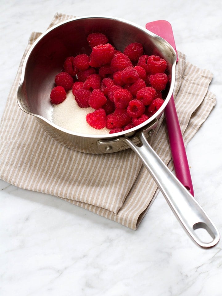 Raspberries and sugar in a saucepan.