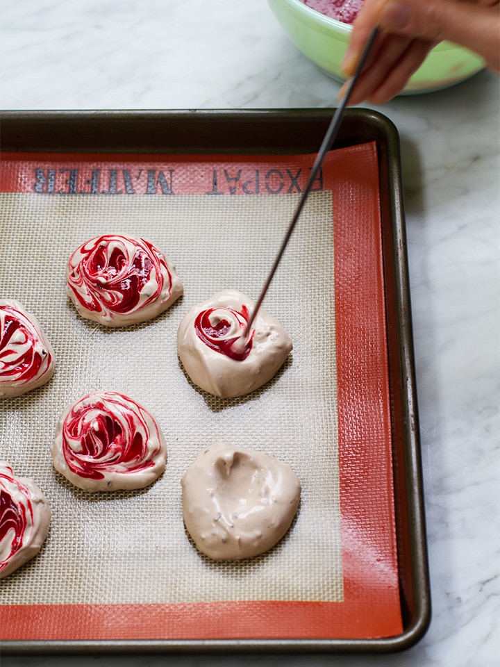Adding raspberry puree to meringues.