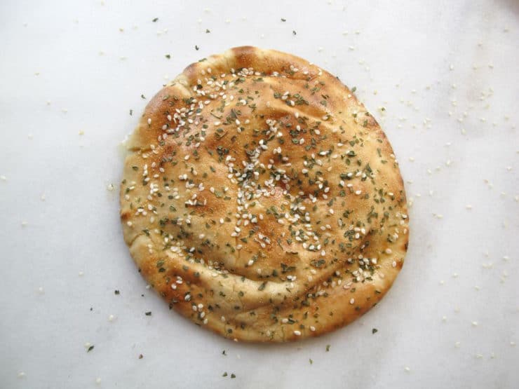 Sesame seeds sprinkled over oiled pita rounds.