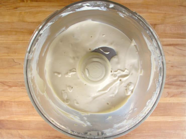 Blending tahini paste, water, lemon juice and salt in a food processor.
