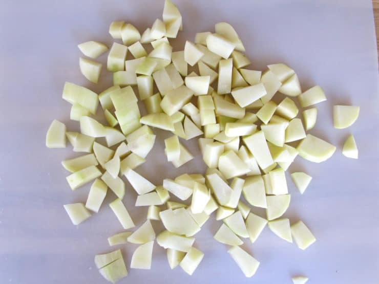 Peeled, diced potatoes on a cutting board.