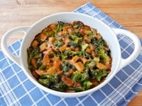 Broccoli Potato Gratin served on a huge white bowl with handles and on top of a blue checkered table clothe