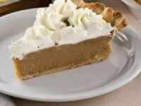 Easy Butterscotch Pie Pinterest Pin - a slice of butterscotch pie topped with whipped cream on a plate with jar of brown sugar, pie place with pie, and a stick of butter in the background.