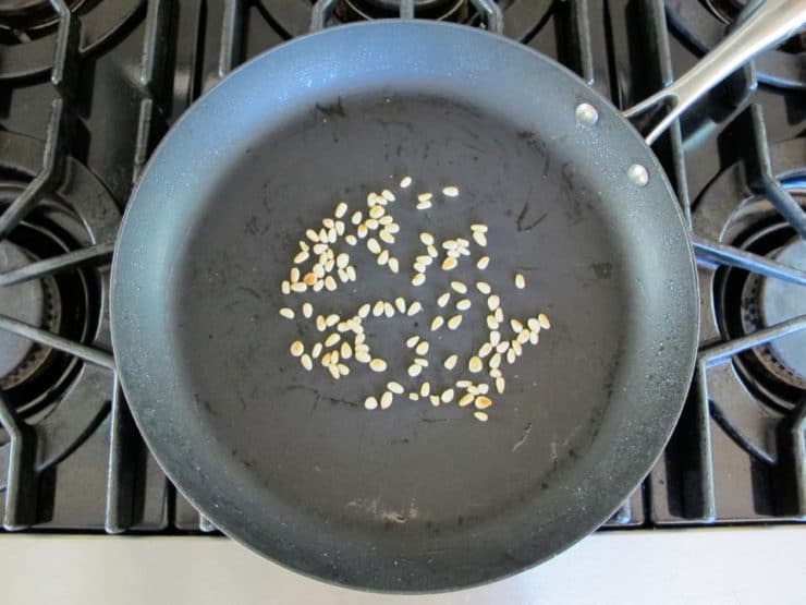 Toasting pine nuts in a skillet.