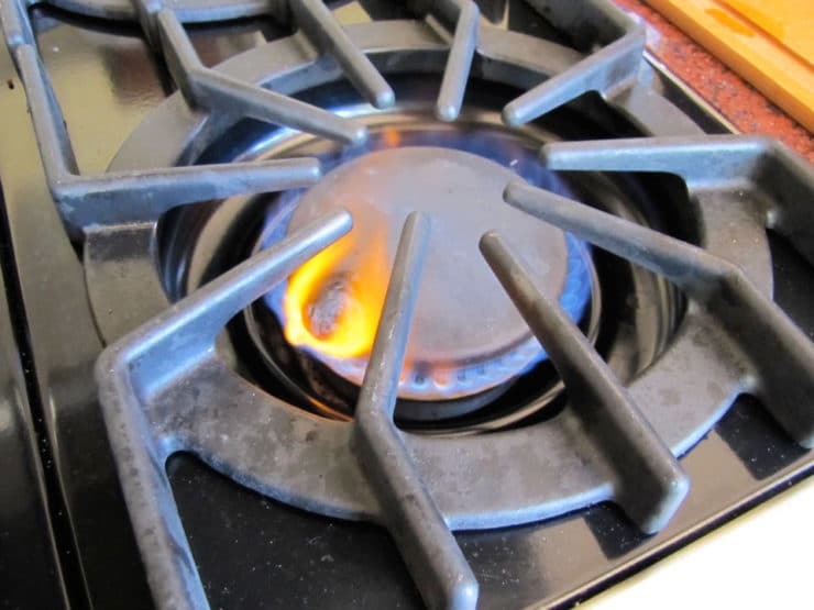 Burning a small portion of dough on gas stovetop as an offering - part of the weekly challah blessing.