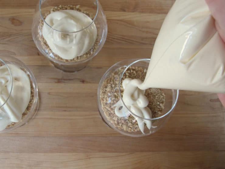 Piping cheesecake mixture on top of graham crust.