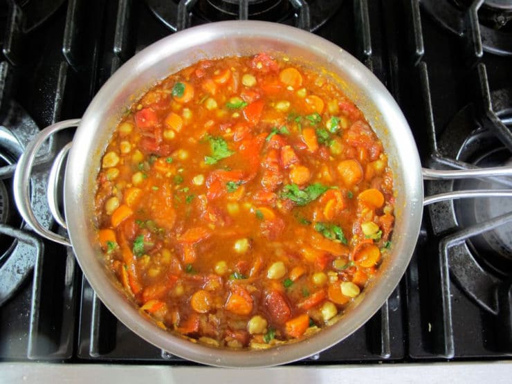 Tomato added to carrots and onion in a skillet.