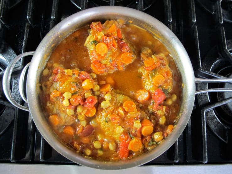 Chicken thighs added to stew in saucepan.