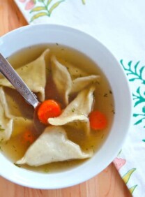 A bowl of chicken soup with dumplings and carrots