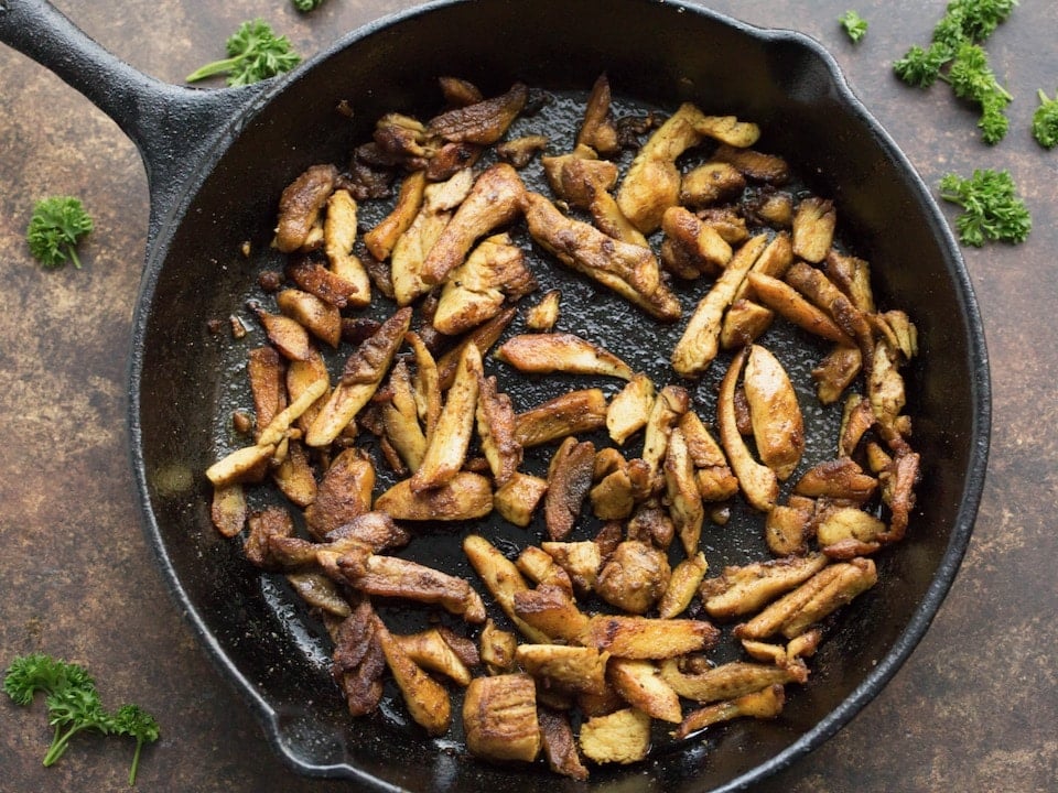Cast iron pan with crispy, juicy cooked chicken shawarma in olive oil. 