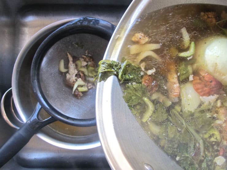 Straining solids from chicken broth.