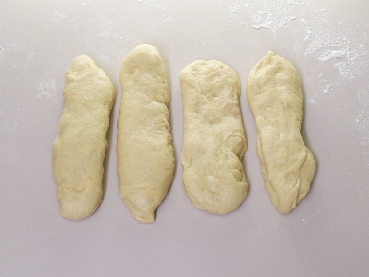 Overhead shot of challah dough separated into 4 rectangular pieces.