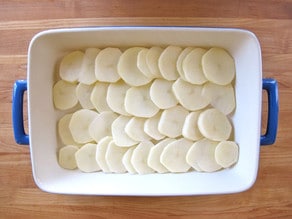 Sliced potatoes in a greased baking dish.