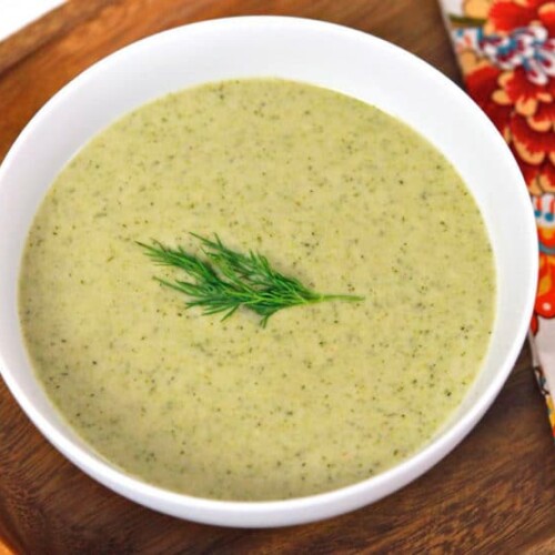 A bowl of Creamy Broccoli Tahini Soup garnished with a dill sprig.