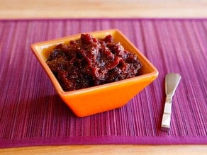 Fig Preserves on a small orange square-shaped bowl with a silver butter spreader knife