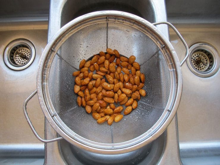 Overhead shot of wet almonds draining in mesh strainer colander.