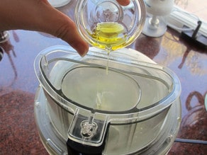 Slowly drizzling oil into running food processor.