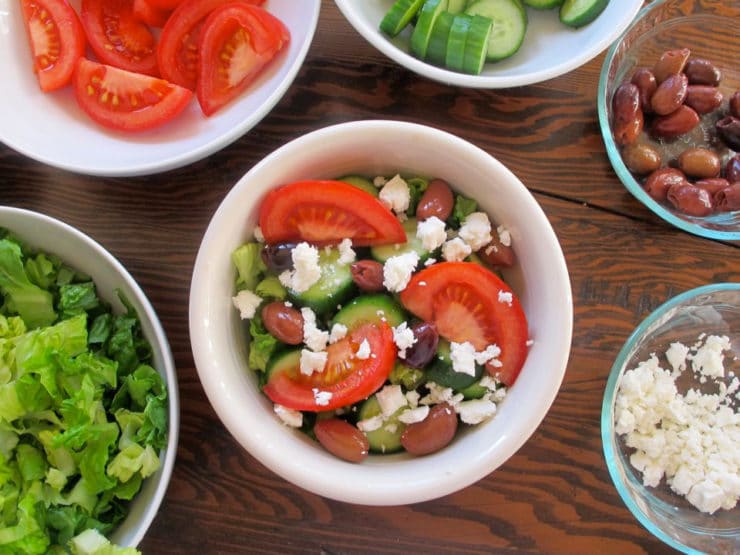 Adding tomatoes and feta to a quinoa bowl.