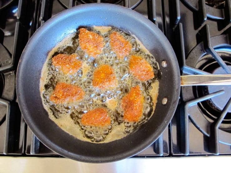 Frying chicken bites in a skillet.