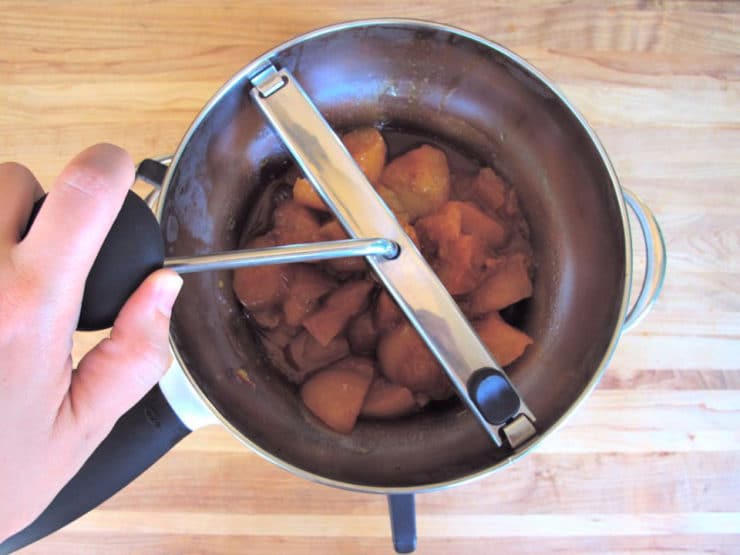 Processing cooked peaches through a food mill.