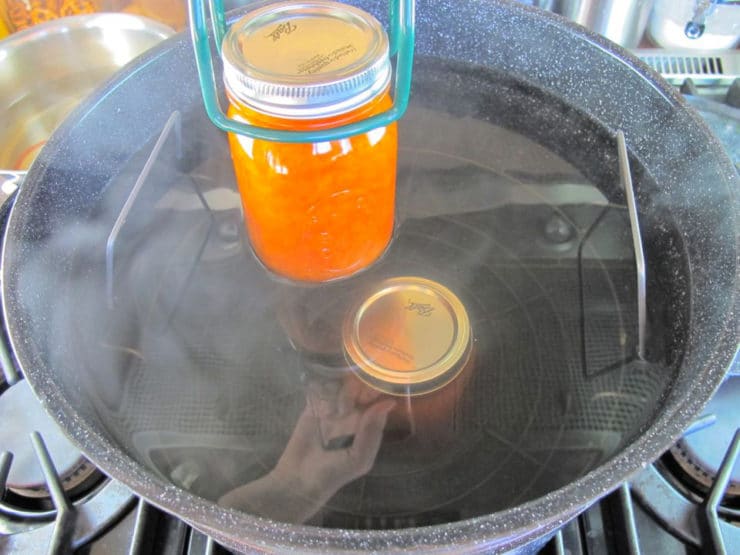 Adding jars of preserves to hot water bath.