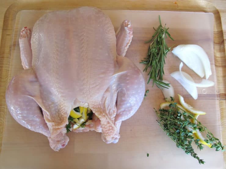 Putting aromatics inside chicken cavity.