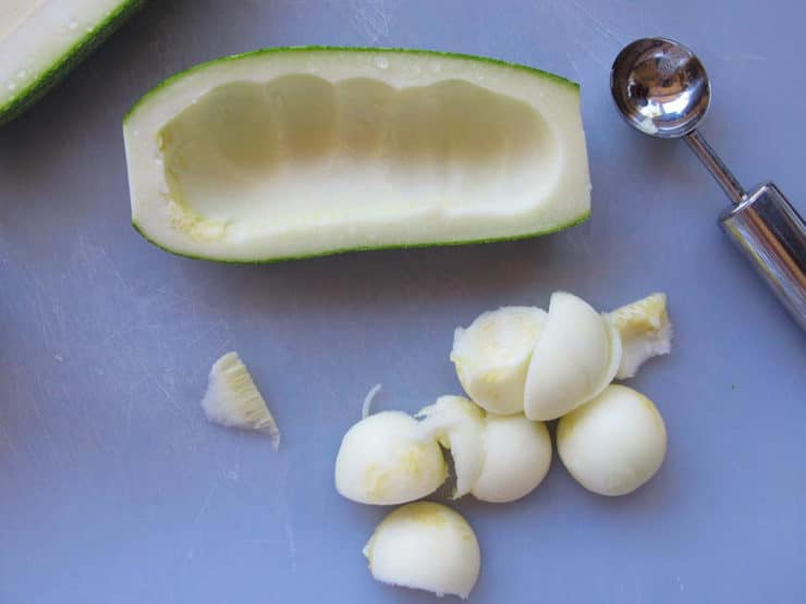 Using a melon baller inside a zucchini.