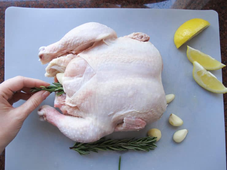 Adding aromatics to chicken cavity.