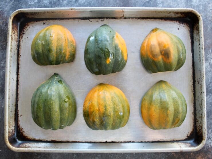 Six acorn squash halves on a baking sheet, cut side downward, skin side up.