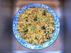 Middle Eastern Roasted Vegetable Rice is presented in a blue speckled bowl, revealing chickpeas, rice, eggplant, and herbs.