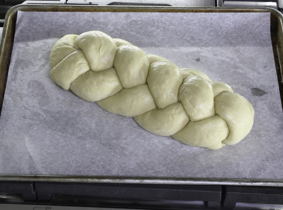 Braided dough resting on a baking sheet, ready for baking.
