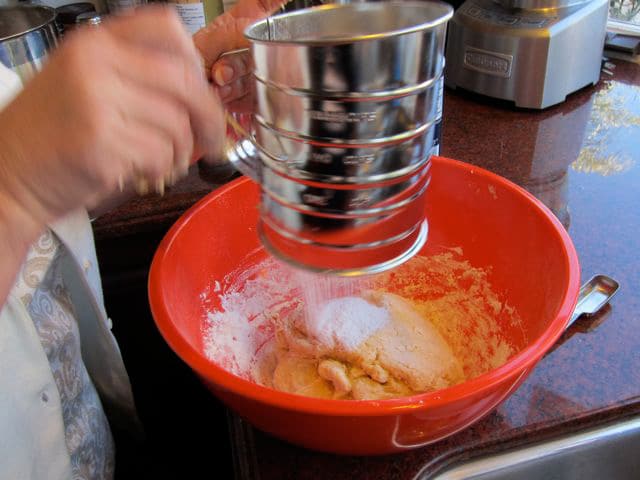 Sifting flour into a mixing bowl.