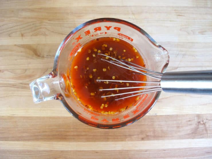 Whisking together tomato sauce in a measuring cup.