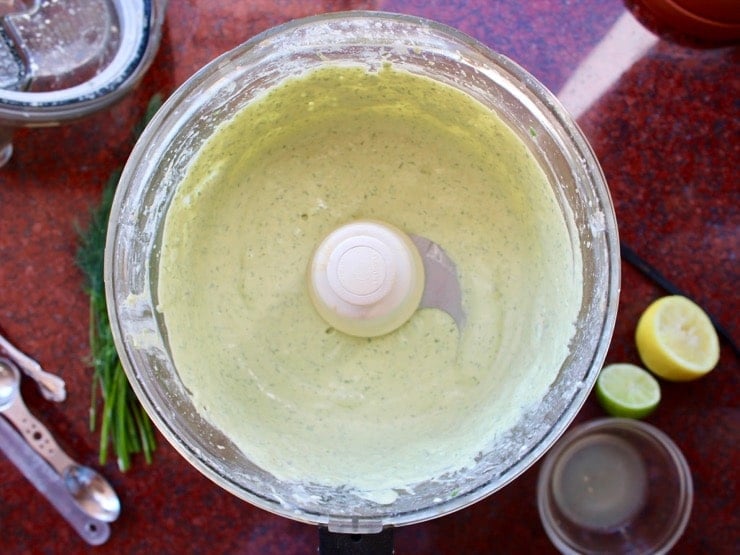 Overhead shot of food processor with blended creamy Herb Tahini Sauce inside.