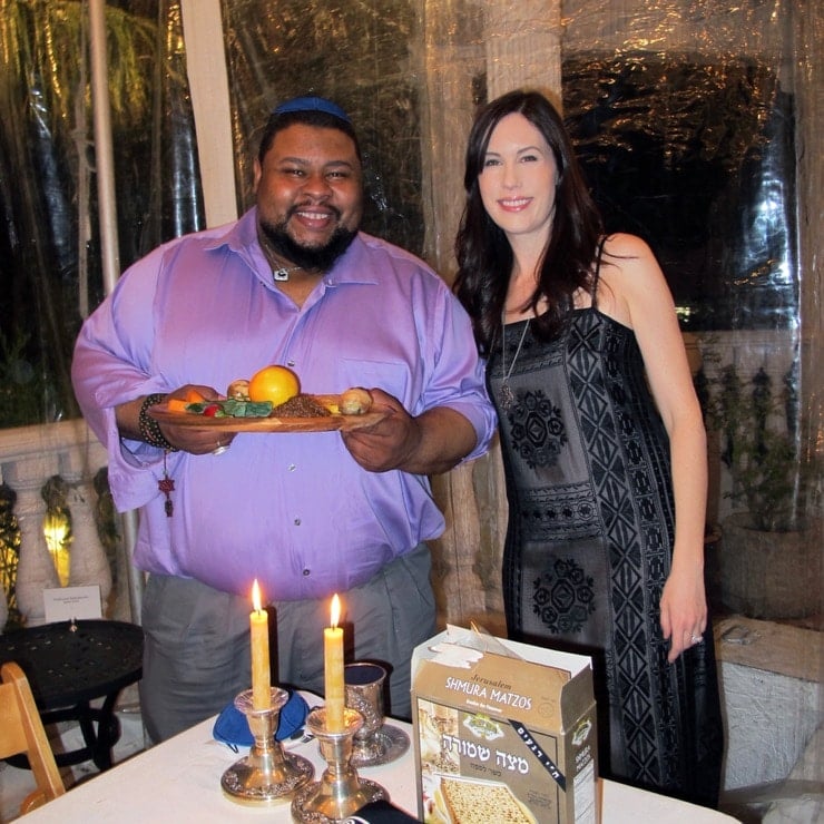 Michael Twitty and Tori Avey at Passover Seder 2017 - Michael holding African American Seder Plate, candles and matzo on table in foreground.