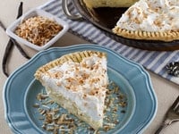 A slice of Coconut Cream Pie on a blue plate, showcasing its creamy filling and golden crust