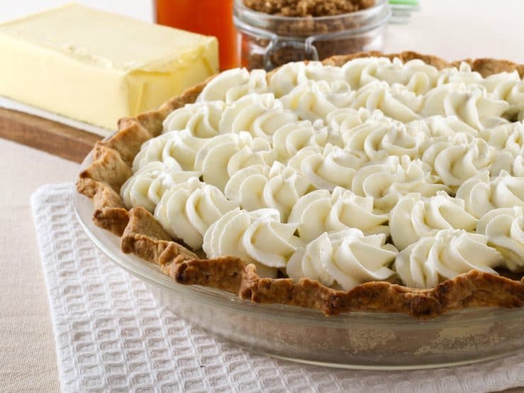 Butterscotch Pie topped with butterscotch custard with butter, brown sugar, and simple syrup in the background. 