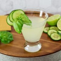 A short cocktail glass filled with a cucumber martini recipe, garnished with slices of fresh cucumber.