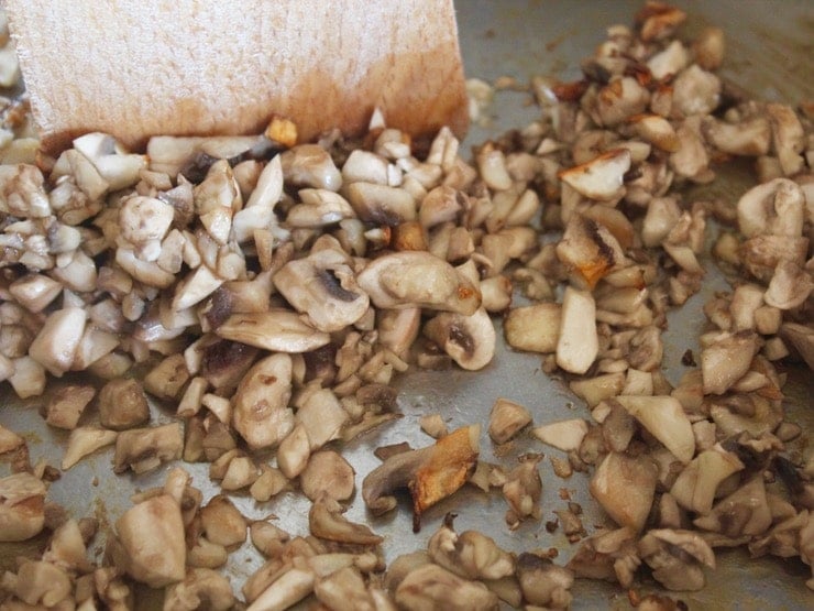 Close up of chopped mushrooms in pan, searing golden brown