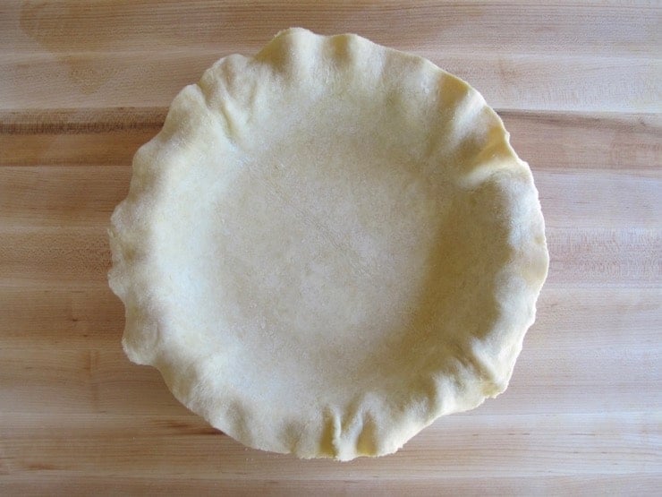 Rolled and trimmed pie crust settled in pie dish.