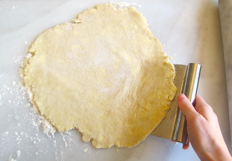 Scraping dough from floured marble surface.