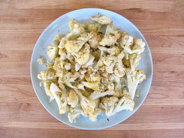 Roasted cauliflower florets cooling on a plate.