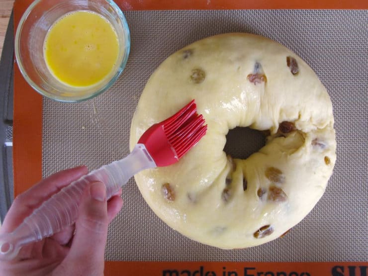 Brushing an egg wash over bread loaf.