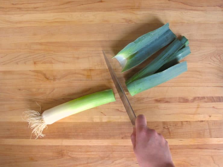 Cutting the dark green section off a leek.
