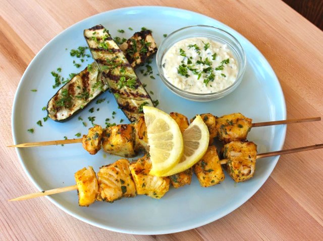 Marinated Fish Skewers with lemon on top and grilled eggplants on side.