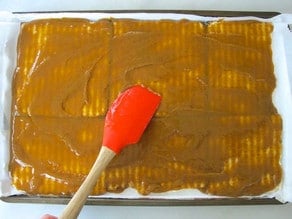 Spreading toffee evenly over matzo.