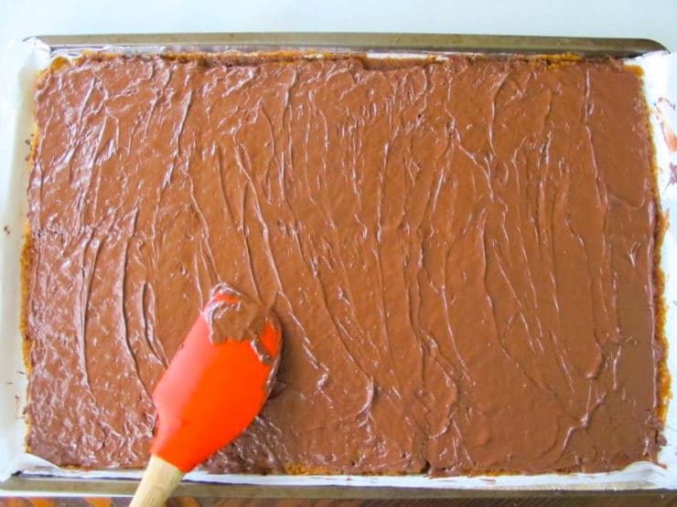 Spreading melted chocolate over toffee matzo.