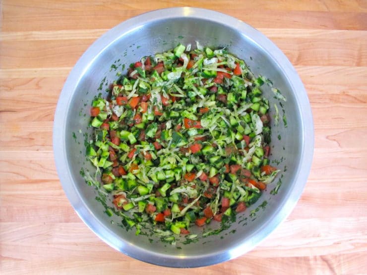 Salad ingredients tossed well in a mixing bowl.