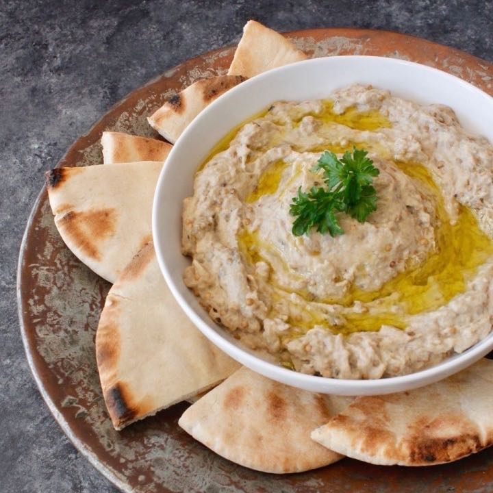 A bowl of baba ganoush surrounded by pita chips. 
