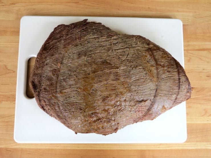 Browned brisket resting on a cutting board.